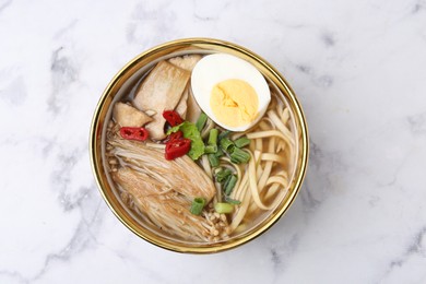 Photo of Tasty ramen with enoki and king oyster (eryngii) mushrooms on white marble table, top view