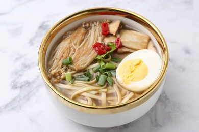Photo of Tasty ramen with enoki and king oyster (eryngii) mushrooms on white marble table, closeup