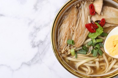 Photo of Tasty ramen with enoki and king oyster (eryngii) mushrooms on white marble table, top view. Space for text