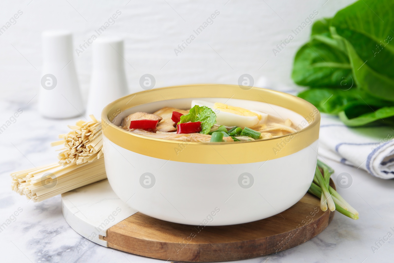 Tasty ramen with enoki and king oyster (eryngii) mushrooms on white marble table, closeup Photo of Tasty ramen with enoki and king oyster (eryngii) mushrooms on white marble table, closeup