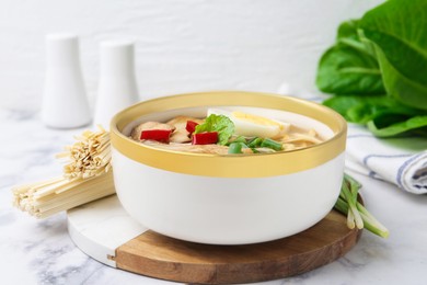 Photo of Tasty ramen with enoki and king oyster (eryngii) mushrooms on white marble table, closeup