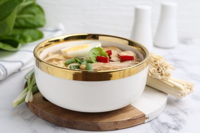 Photo of Tasty ramen with enoki and king oyster (eryngii) mushrooms on white marble table, closeup