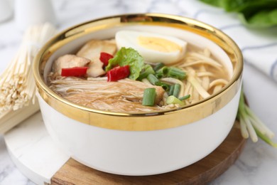 Photo of Tasty ramen with enoki and king oyster (eryngii) mushrooms on white marble table, closeup