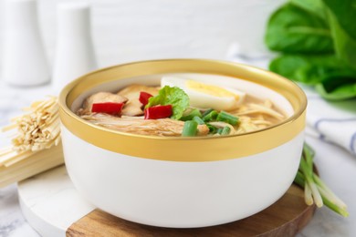 Photo of Tasty ramen with enoki and king oyster (eryngii) mushrooms on white marble table, closeup