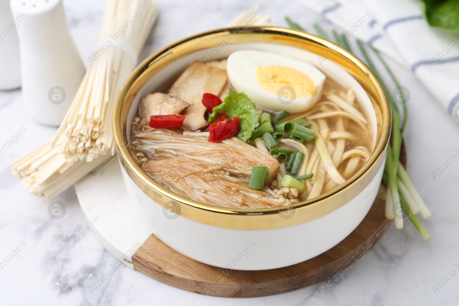 Tasty ramen with enoki and king oyster (eryngii) mushrooms on white marble table, closeup Photo of Tasty ramen with enoki and king oyster (eryngii) mushrooms on white marble table, closeup