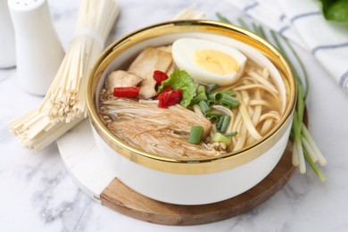 Photo of Tasty ramen with enoki and king oyster (eryngii) mushrooms on white marble table, closeup