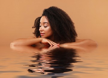 Image of Beautiful woman with perfect skin against pale brown background. Her reflection in rippled water