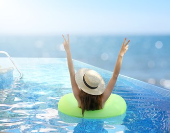 Image of Girl with inflatable ring resting in swimming pool at sea resort