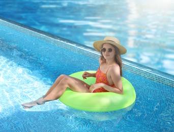 Image of Girl with inflatable ring resting in swimming pool at sea resort