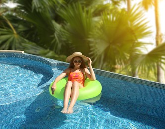 Image of Girl with inflatable ring resting in swimming pool at sea resort