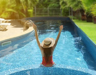 Image of Girl with straw hat in swimming pool at sea resort