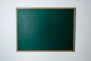 Photo of Blank green chalkboard on white wall indoors