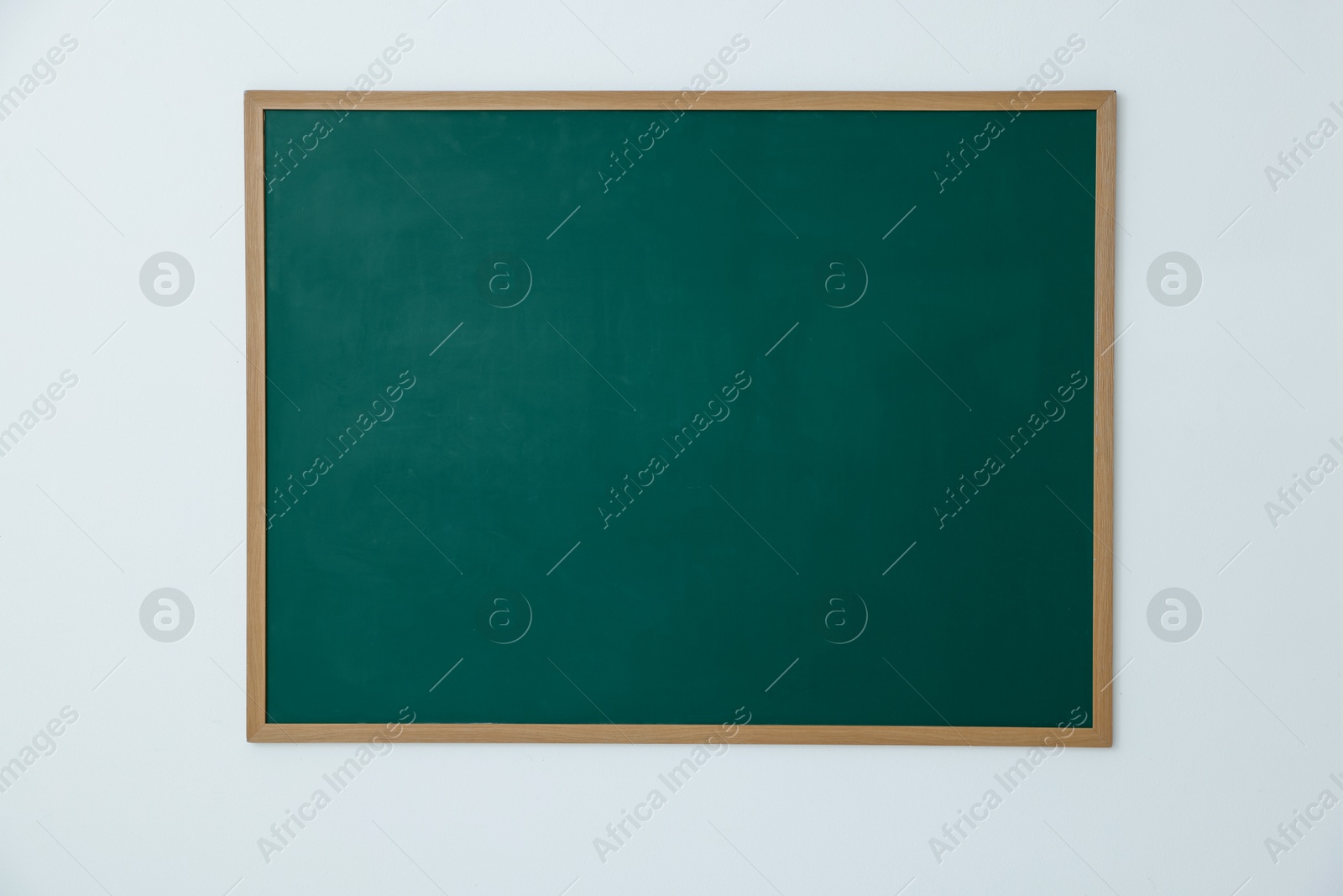 Photo of Blank green chalkboard on white wall indoors