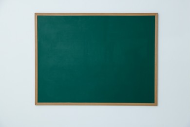 Photo of Blank green chalkboard on white wall indoors