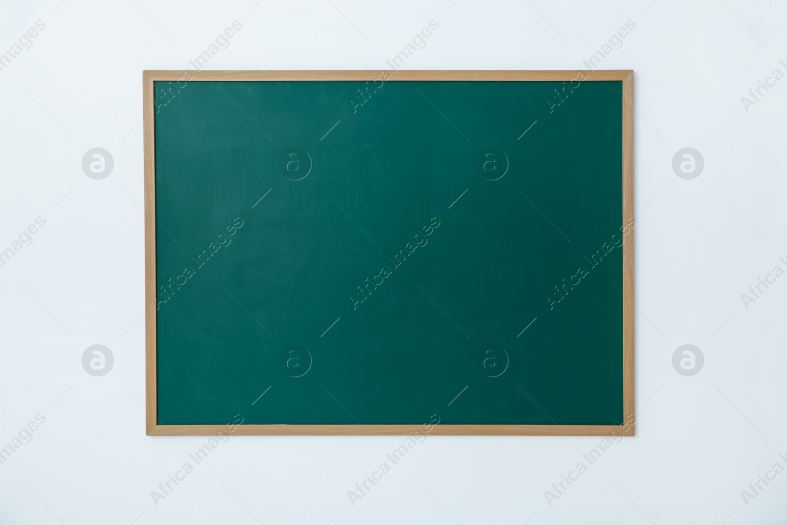 Photo of Blank green chalkboard on white wall indoors
