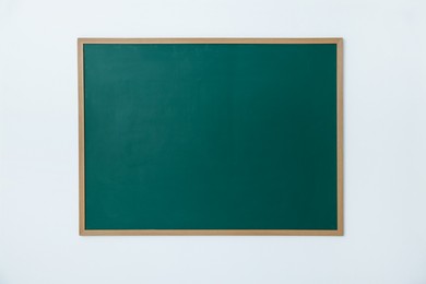 Photo of Blank green chalkboard on white wall indoors
