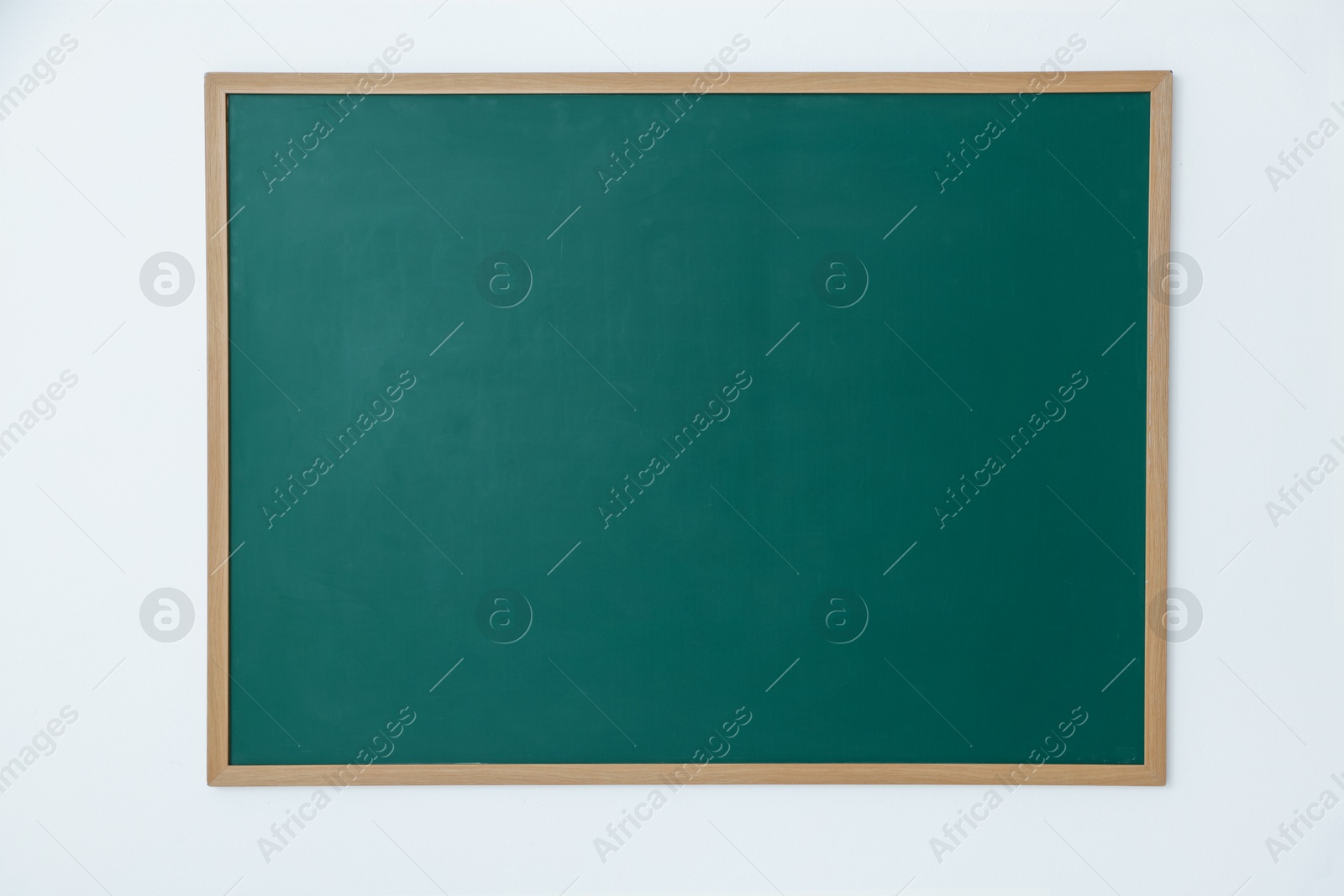 Photo of Blank green chalkboard on white wall indoors