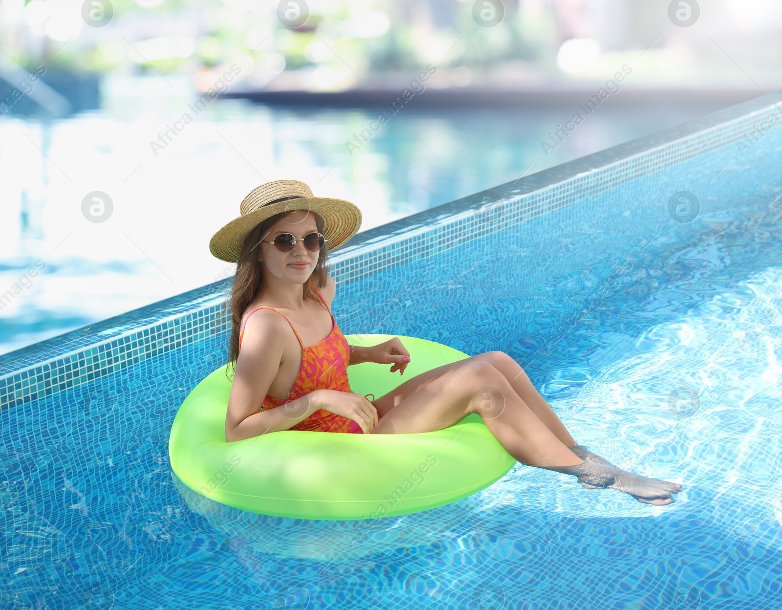 Image of Girl with inflatable ring resting in swimming pool at sea resort