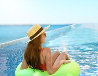 Image of Girl with inflatable ring resting in swimming pool at sea resort