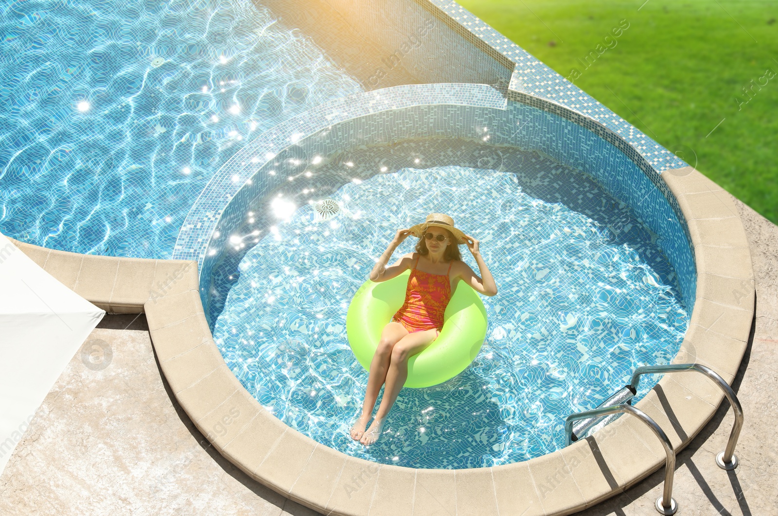 Image of Girl with inflatable ring resting in swimming pool at sea resort
