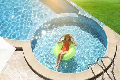 Image of Girl with inflatable ring resting in swimming pool at sea resort