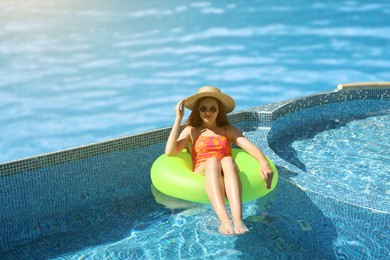 Image of Girl with inflatable ring resting in swimming pool at sea resort