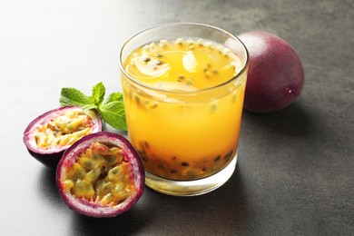Photo of Tasty passion fruit drink with mint and fresh fruits on grey table, closeup