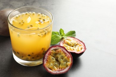 Photo of Tasty passion fruit drink with mint and fresh fruits on grey table, closeup. Space for text