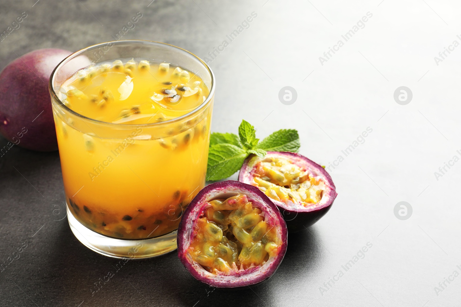 Tasty passion fruit drink with mint and fresh fruits on grey table, closeup. Space for text Photo of Tasty passion fruit drink with mint and fresh fruits on grey table, closeup. Space for text
