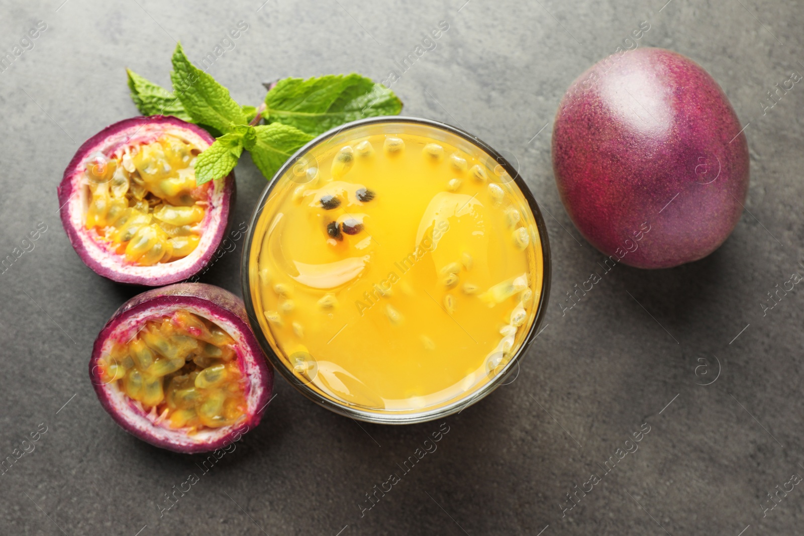 Photo of Tasty passion fruit drink with mint and fresh fruits on grey table, flat lay