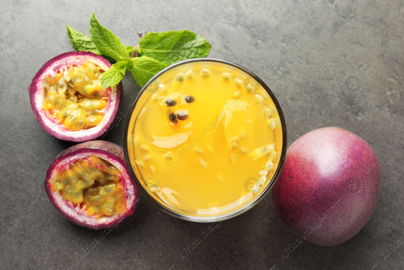 Photo of Tasty passion fruit drink with mint and fresh fruits on grey table, flat lay
