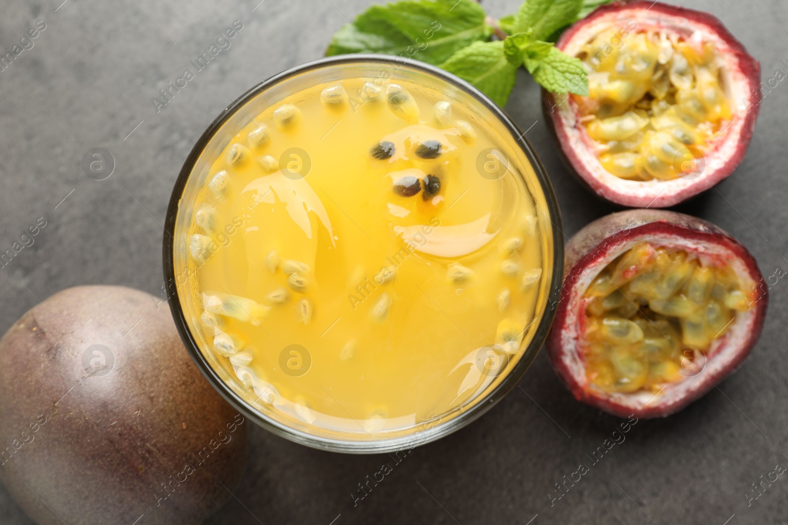 Photo of Tasty passion fruit drink with mint and fresh fruits on grey table, flat lay