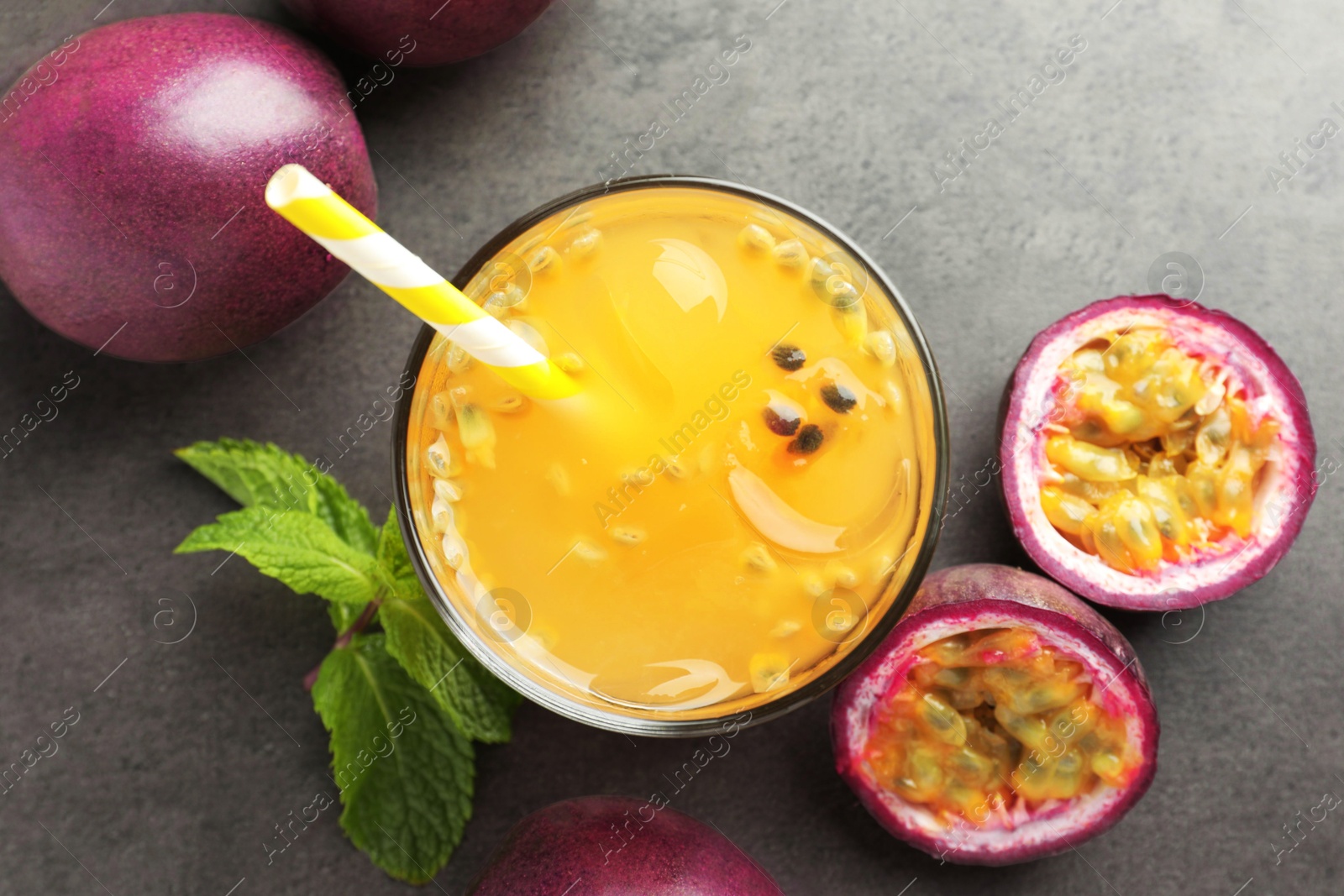 Photo of Tasty passion fruit drink with mint and fresh fruits on grey table, flat lay