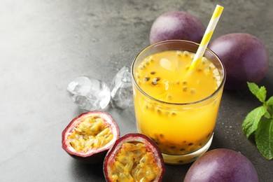 Photo of Tasty passion fruit drink with mint, ice cubes and fresh fruits on grey table, closeup. Space for text