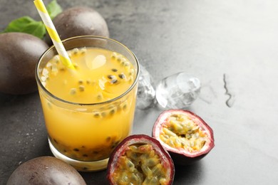 Photo of Tasty passion fruit drink with ice cubes and fresh fruits on grey table, closeup. Space for text