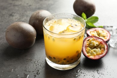 Photo of Tasty passion fruit drink with mint and fresh fruits on grey table, closeup