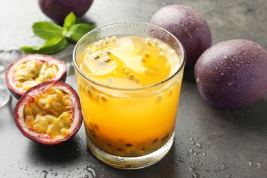 Photo of Tasty passion fruit drink with mint and fresh fruits on grey table, closeup