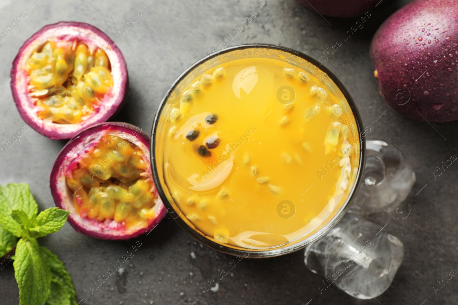 Photo of Tasty passion fruit drink with mint and fresh fruits on grey table, flat lay