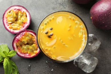 Photo of Tasty passion fruit drink with mint and fresh fruits on grey table, flat lay