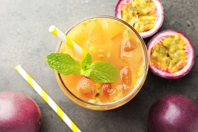 Photo of Tasty passion fruit drink with mint and fresh fruits on grey table, flat lay