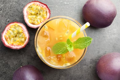 Photo of Tasty passion fruit drink with mint and fresh fruits on grey table, flat lay