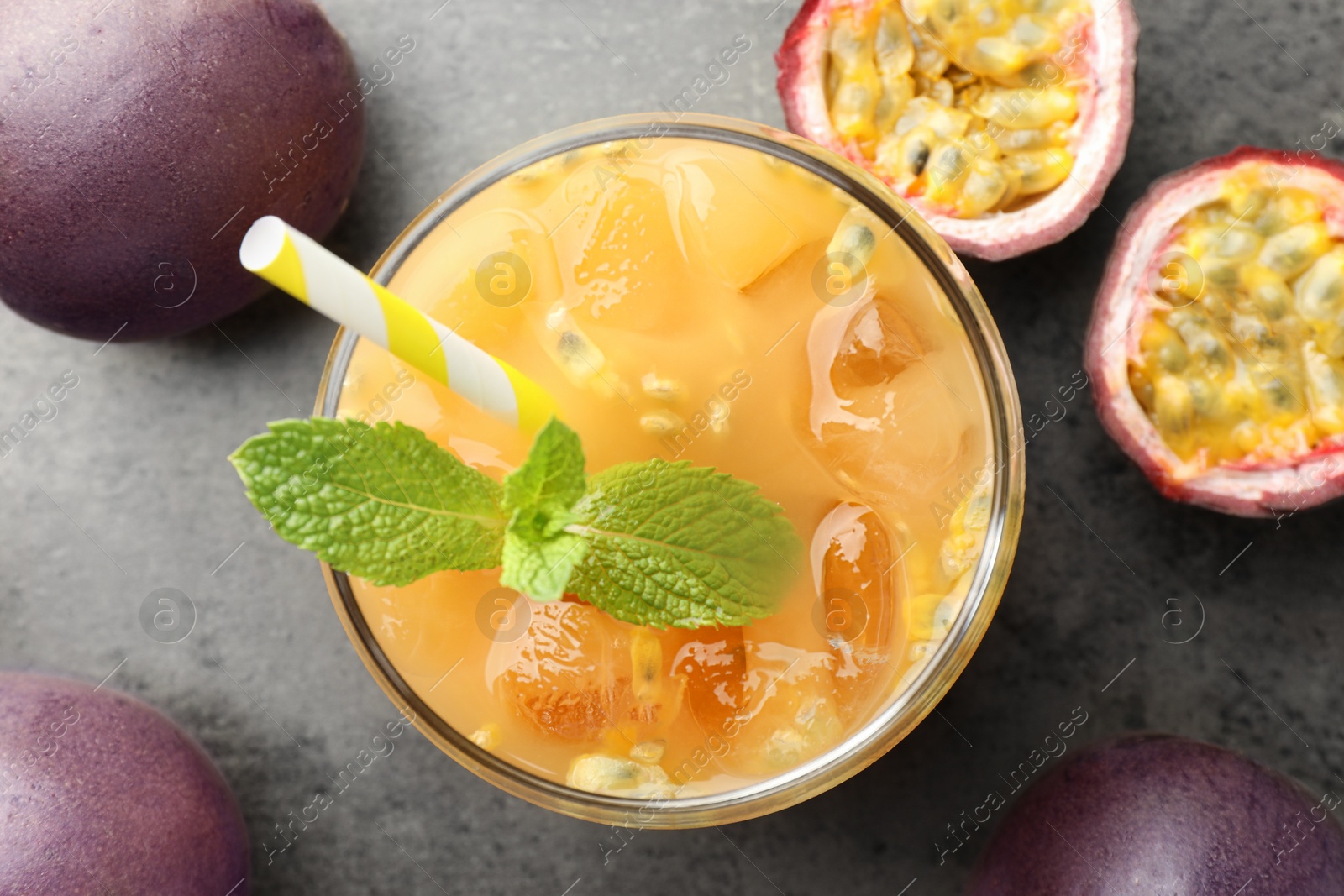 Photo of Tasty passion fruit drink with mint and fresh fruits on grey table, flat lay