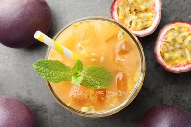 Photo of Tasty passion fruit drink with mint and fresh fruits on grey table, flat lay