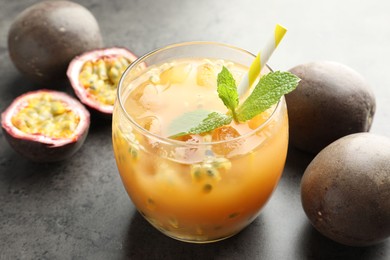 Photo of Tasty passion fruit drink with mint and fresh fruits on grey table, closeup