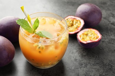 Photo of Tasty passion fruit drink with mint and fresh fruits on grey table, closeup