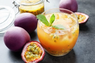 Photo of Tasty passion fruit drink with mint and fresh fruits on grey table, closeup