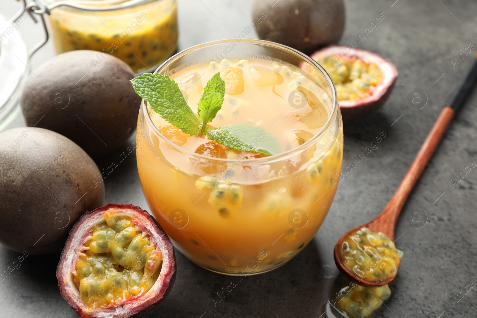 Photo of Tasty passion fruit drink with mint and fresh fruits on grey table, closeup