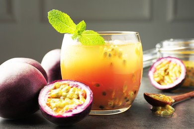 Photo of Tasty passion fruit drink with mint and fresh fruits on grey table, closeup