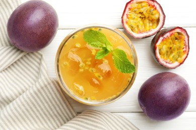 Photo of Tasty passion fruit drink with mint and fresh fruits on white wooden table, flat lay