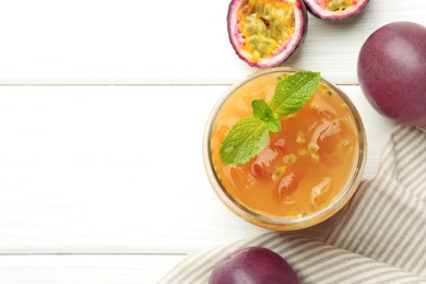 Photo of Tasty passion fruit drink with mint and fresh fruits on white wooden table, flat lay. Space for text